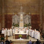 Father Raymond Brenner, center, stands at the altar with deacons Levi Schnellenberger, left, and Martin Estrada, at the beginning of the Eucharistic Prayer. At the back left are his great nephews Jonathan Brenner, left, and Timothy Brenner, altar servers for the May 19 Mass. Standing on the altar with them are concelebrants Fathers Ron Kreilein, left, Eugene Schmitt, Bill Traylor, Joe Ziliak, Christopher Droste, Tony Ernst, Dave Martin, Lowell Will, John Boeglin, John Brosmer, Pat Gaza, Anthony Govind, Crispine Adongo, Jim Koressel, Steve Lintzenich, Tim Tenbarge, John Schipp and Joseph Erbacher. At the far right is Director of St. Joseph Youth Choir Mary Burke, who served as cantor.