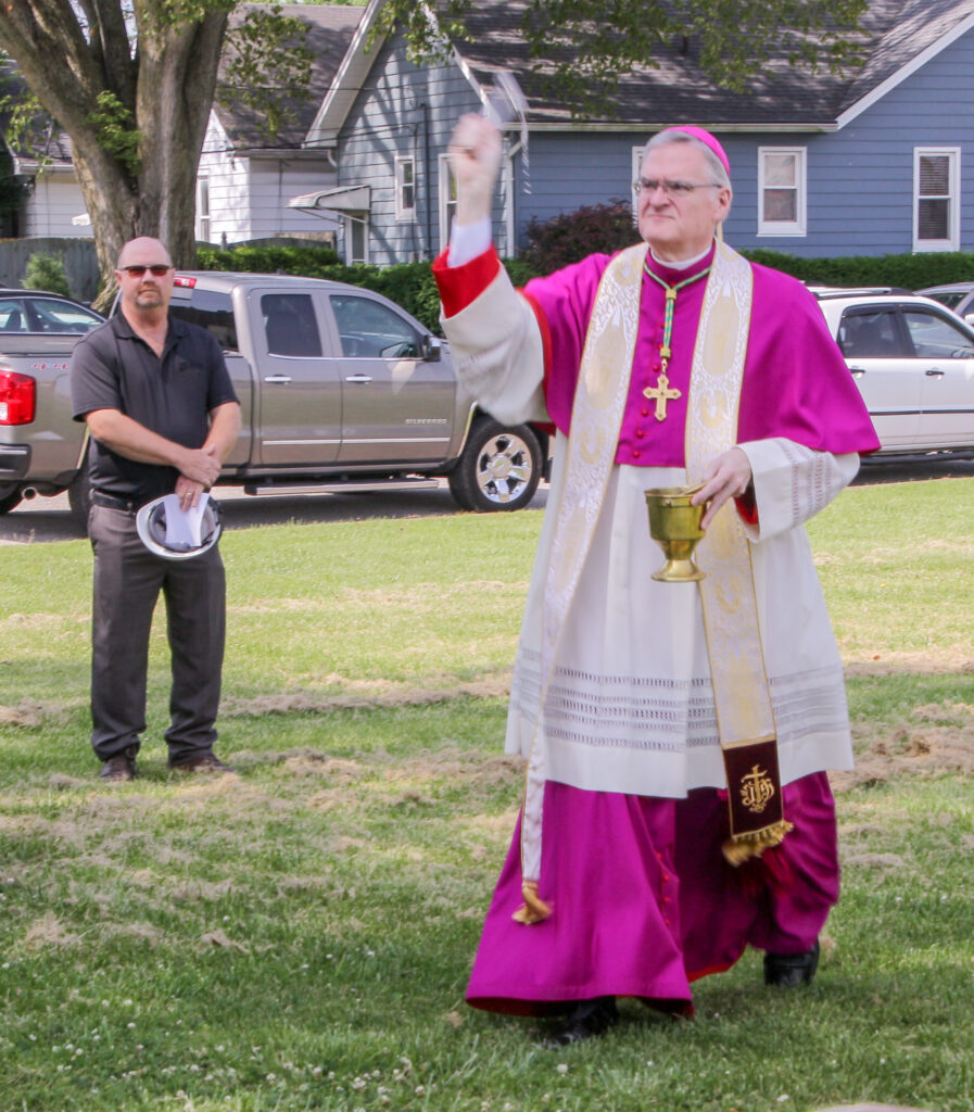 Bishop Siegel sprinkles holy water around the grounds of the future home of Catholic Charities during the June 3 groundbreaking ceremony.