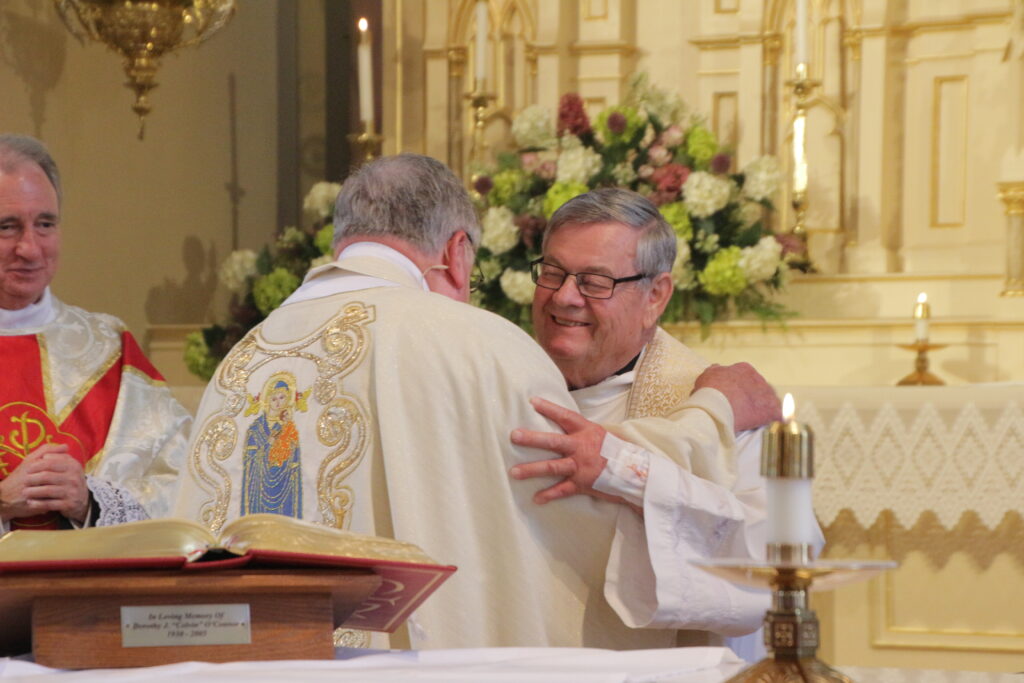 Father Koressel, left, shares the sign of peace with his classmate, Father Ray Brenner. Father Brenner, who also retires from pastoral ministry this month, is pastor of St. Joseph Parish in Jasper and Dean of the Diocese of Evansville East Deanery.