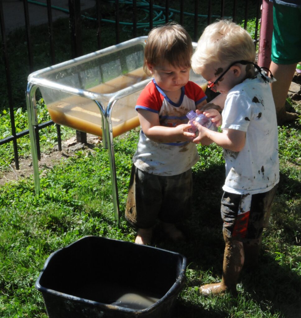 Tristan Clapp, left, and Phillip Hyndman play with muddy water during St. Vincent Early Learning Center’s celebration of International Mud Day.