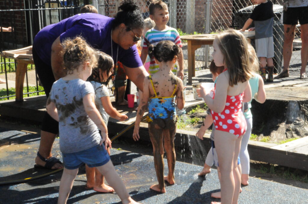 Alissa Mwenelupembe, St. Vincent Early Learning Center director of early learning, hoses mud off of some kids during the center’s celebration of International Mud Day on June 28.