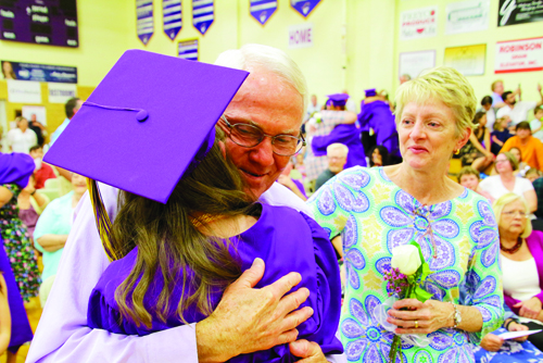 Rivet High School Class of 2019 President Savannah Cook hugs her father Joe,
left, as her mother Janet looks on. Savannah joined her classmates in presenting flowers and hugs of gratitude to their parents during Commencement.
Janet is holding the flower Savannah gave her with a huge hug.