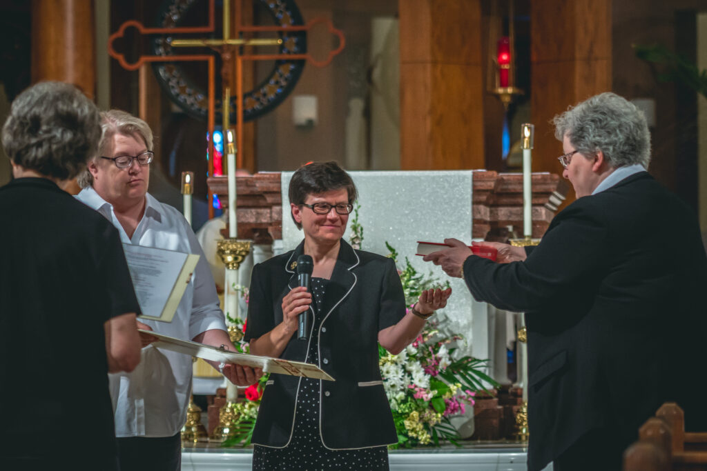 Benedictine Sister Barbara Lynn Schmitz, right, presents Sister
Anita Louise Lowe with the Book of the Gospels during her
installation as prioress — replacing Sister Barbara Lynn — during a July 13 Mass at Monastery Immaculate Conception.
