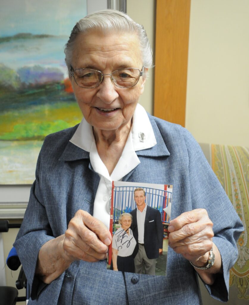 Daughter of Charity Sister Mary John Tintea holds an old photograph of herself with Former NFL quarterback Peyton Manning, which he autographed after the press conference.