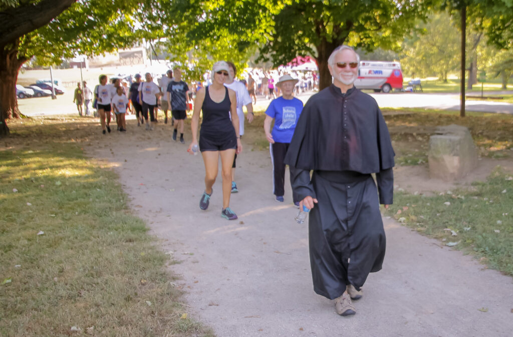 Longtime Vincentian Tim Gehlhausen, dressed at St. Vincent de Paul, leads more than 350 walkers
on their way at the start of the 12 th Annual Friends of the Poor Walk Sept. 21 on the grounds of Evansville State Hospital. Gehlhausen took over for the late Vince Brenner, who attended several walks as St. Vincent de Paul to welcome and support walkers and their families. The Message photo by Tim Lilley