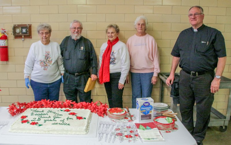 Deacon Lambert, second from left, prepares to cut the cake made in his honor. Joining him are WESK volunteers and Father Jack Durchholz, pastor of St. Clement Parish.
The Message photo by Tim Lilley