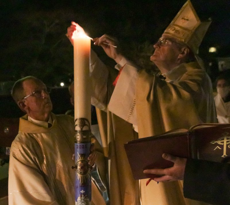 Bishop Siegel lights the Paschal Candle, being held by Deacon David Rice, outside the Cathedral at the beginning of the vigil. The Message photo by Tim Lilley