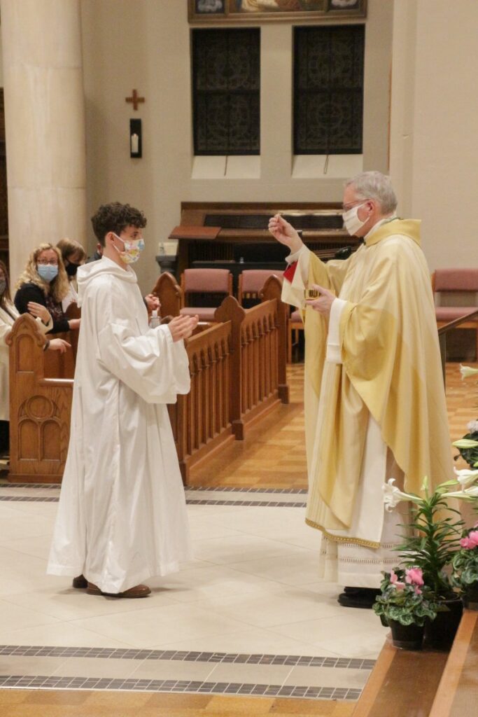 Gabriel Boeglin, who was baptized and confirmed during the Mass, receives First Holy Communion from Bishop Siegel. The Message photo by Tim Lilley