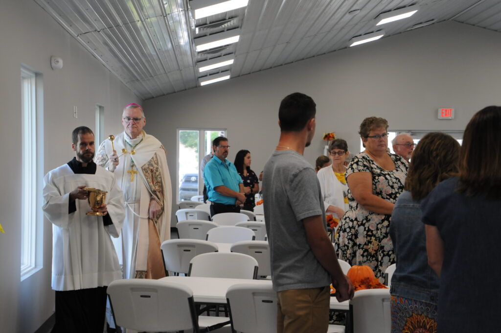 Bishop Joseph M. Siegel sprinkles holy water throughout St. Philip Neri’s new parish hall during a dedication and blessing Aug. 29. Matt Miller, diocesan director of the Office of Worship, assists the bishop. The Message photo by Megan Erbacher
