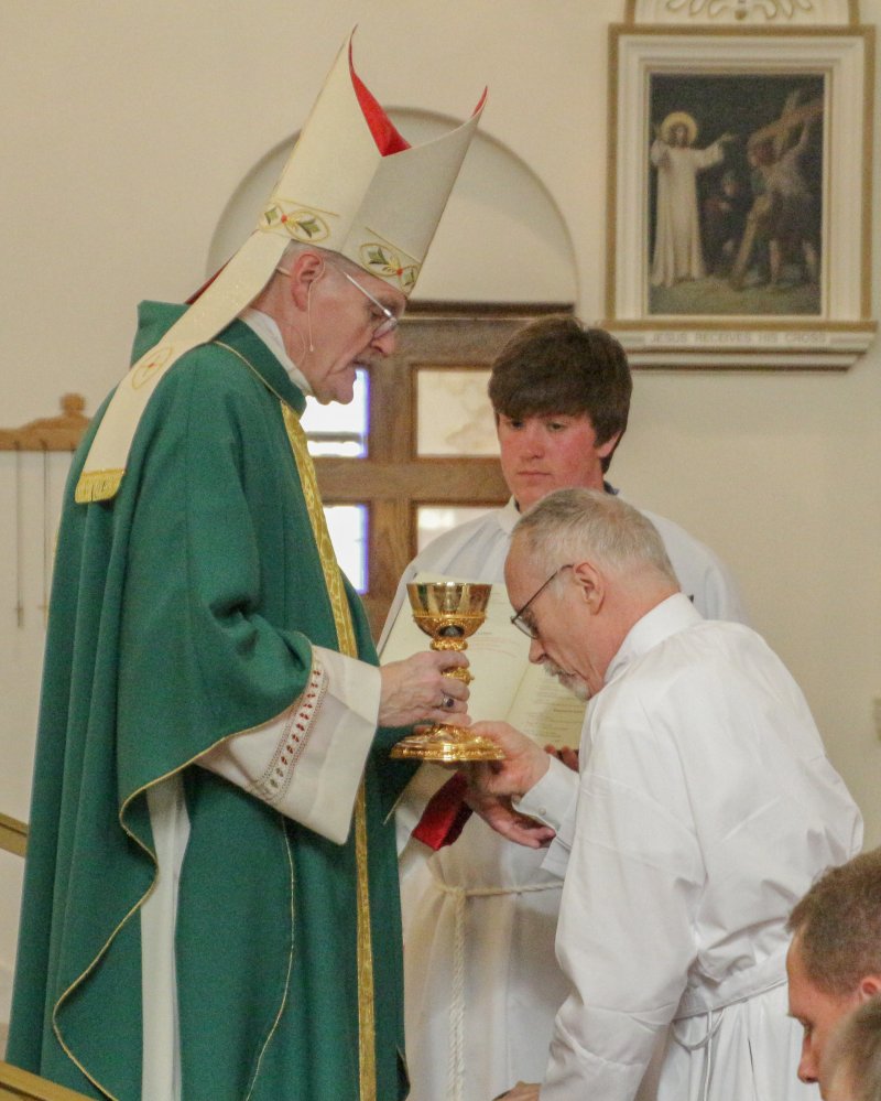 Diaconate Candidate Kevin Kilmer of St. Francis Xavier Parish
in Vincennes holds the chalice used in the celebration of Mass
as Bishop Siegel prays over him. The bishop repeated this for
all 12 candidates. The Message photo by Tim Lilley