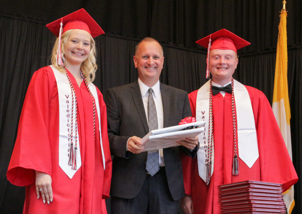 Dr. Daryl Hagan, center, who is leaving his position as diocesan superintendent of schools in early July to
join the Catholic University of America, accepts a gift from Washington Catholic High School Senior Class President Alyssa Davison, left, and Vice-President Logan Craney. Washington Catholic held its Commencement ceremony for the class of 2022 May 21. The Message photo by Tim Lilley