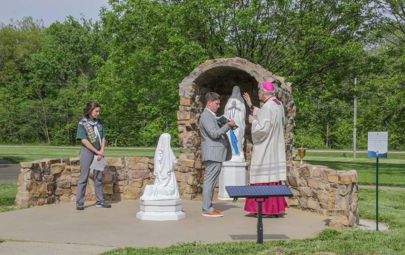 Bishop Joseph M. Siegel blesses the shine to Our Lady of Lourdes and St. Bernadette Soubirous at the conclusion of the May 8 Eagle Scout ceremony for Nicole Payne, left. Her brother and fellow Eagle Scout, Daniel, holds the book of prayers. The Message photo by Tim Lilley