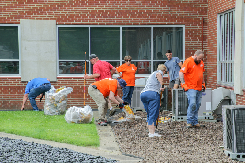 Volunteers near completion of the May 19 project as they install gravel along the east side of the Catholic Center building. The Message photo by Tim Lilley